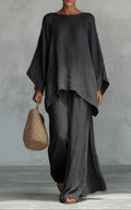 Person wearing a black outfit holding a woven bag against a gray background