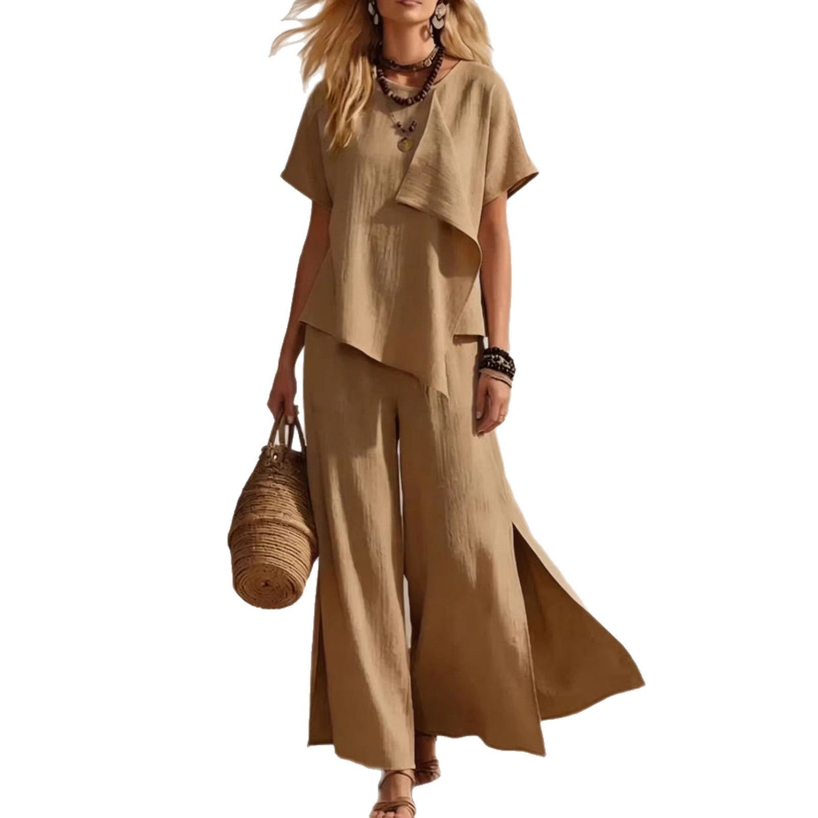 Woman wearing a beige outfit with wide-leg pants and a top, holding a woven bag on a white background.