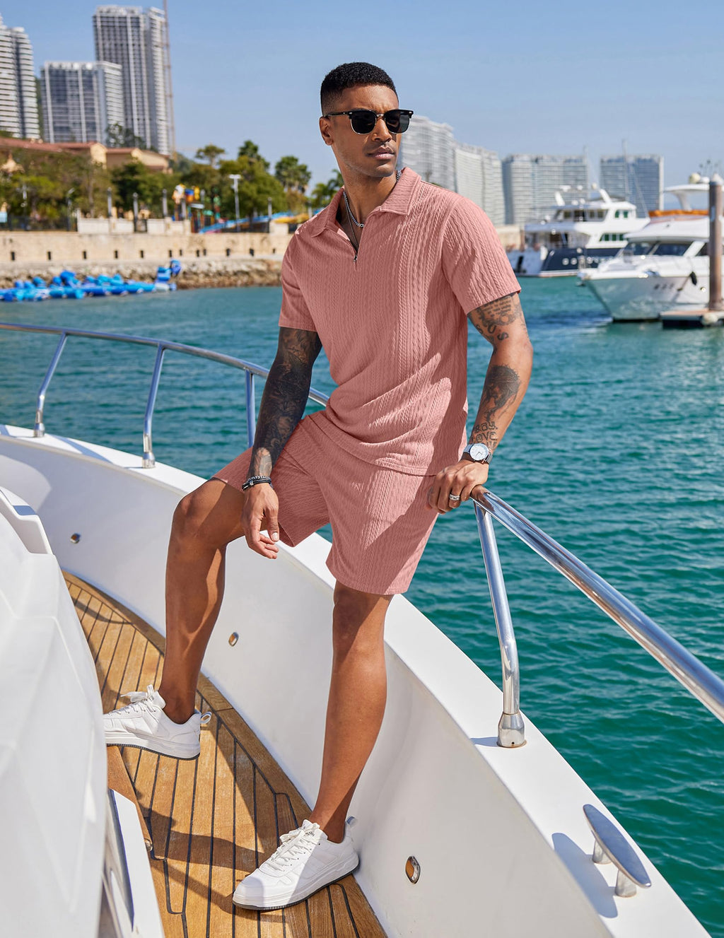 Man in pink outfit on a boat with cityscape in the background