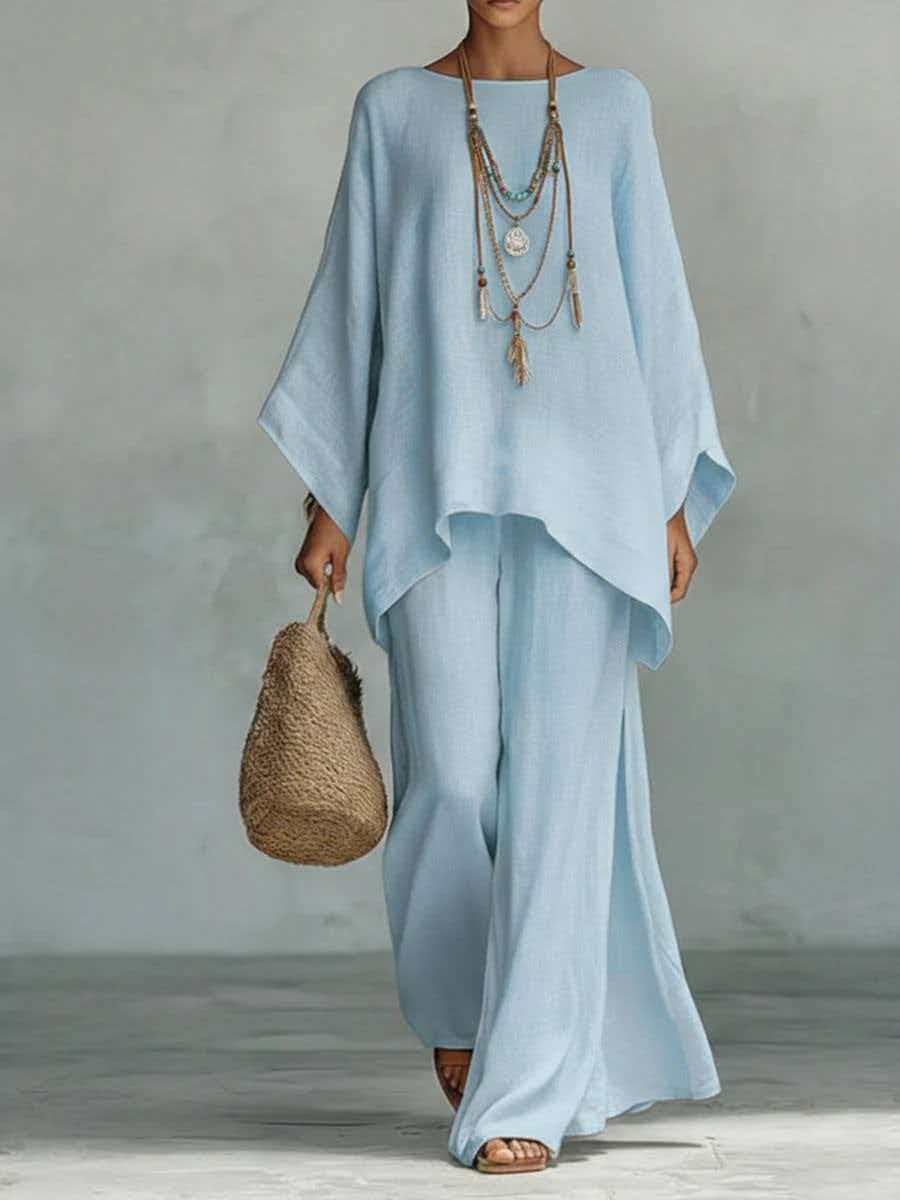 Woman wearing a light blue outfit holding a woven bag against a neutral background