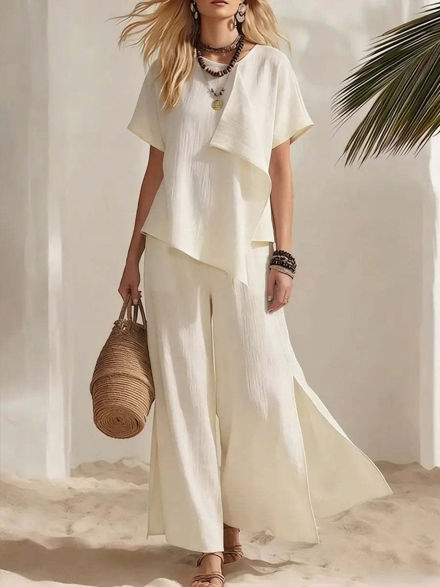 Woman in a white outfit holding a woven bag on a beach.