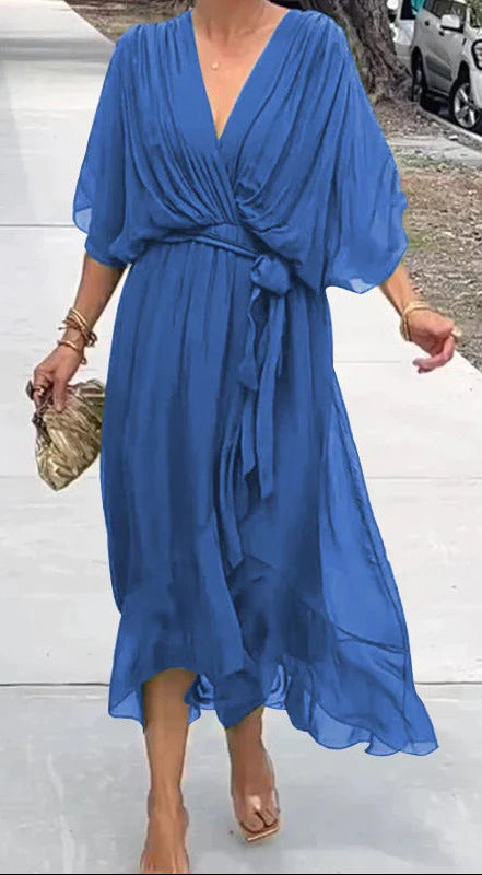 Woman wearing a blue dress walking on a sidewalk.