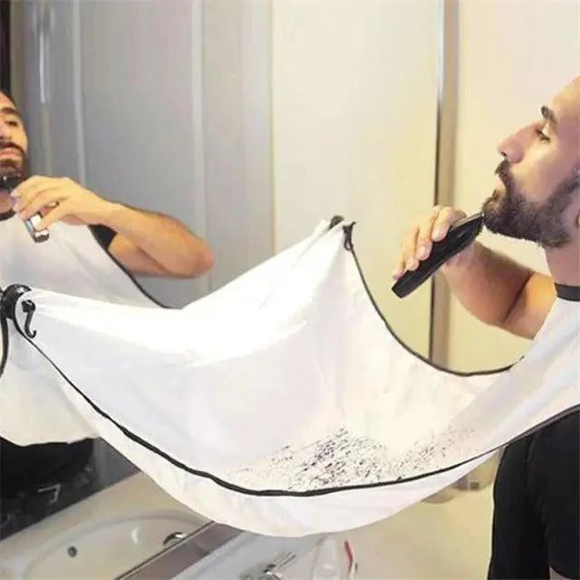 Man using an electric razor with a white bib draped over his shoulders in front of a mirror.